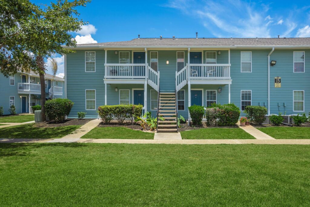Exterior of Palm Isle Apartments in Biloxi, Mississippi, located at the edge of a well-maintained green lawn